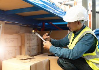 Portrait An Asian warehouse worker in a blue security suit holding clipboard working at store industry. Logistic import export concept Distribution Center. Logistics and export of business